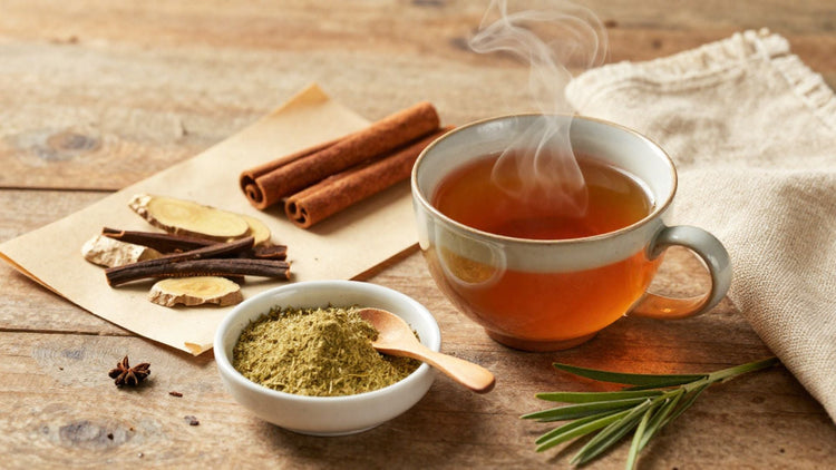 Steaming herbal tea, herbal powder, and warming spices arranged on aged wood in soft morning light — a daily ritual of nourishment for body and soul.